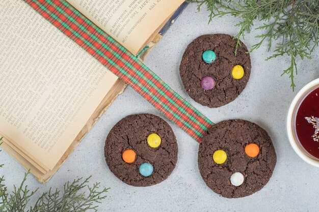 Taza de aroma blanco de té de hierbas con galletas de chocolate sobre superficie gris