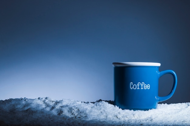 Foto gratuita taza azul en banco de nieve