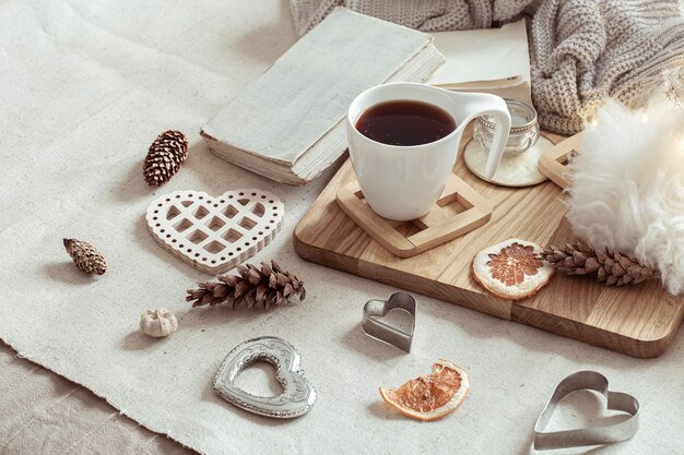 Una taza de bebida caliente y bonitos artículos de decoración para el hogar. El concepto de confort y estética del hogar.