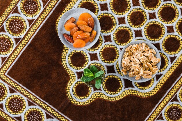 Taza de bebida cerca de frutas secas y nueces en estera