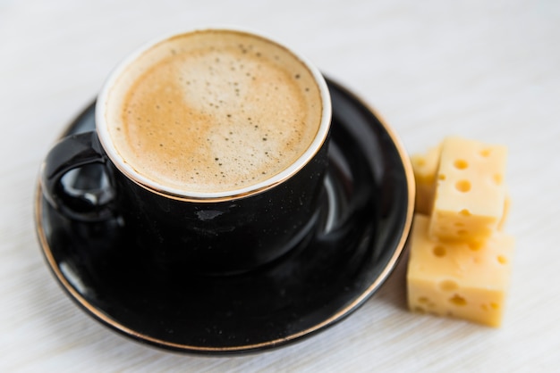 Taza de bebida cerca de queso en la mesa