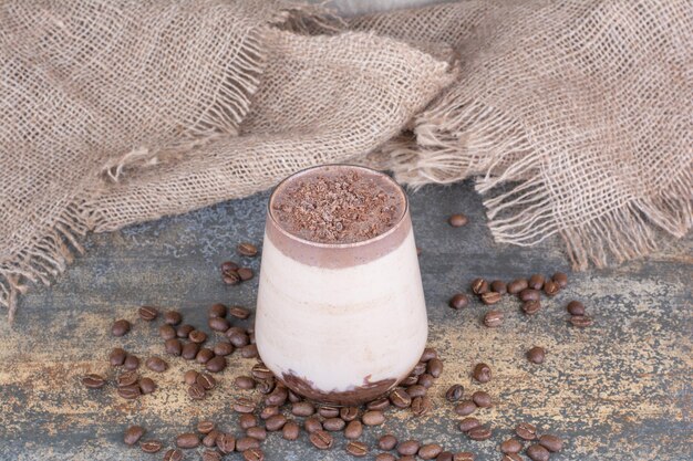 Una taza de bebida deliciosa con granos de café sobre mármol.