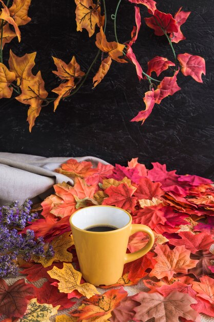 Taza con bebida en hojas de otoño