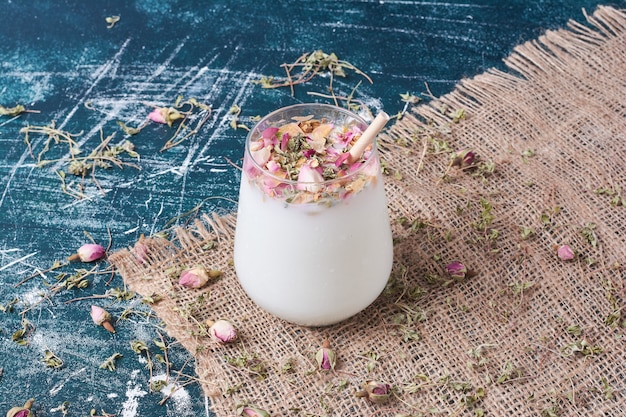 Una taza de bebida lechosa con frutas y hierbas en azul.