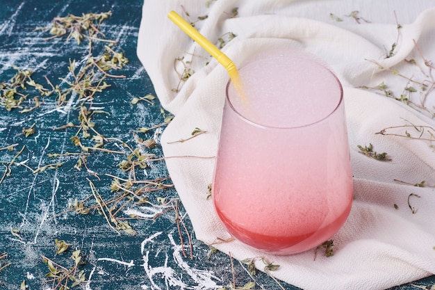 Foto gratuita una taza de bebida rosa con espuma espesa sobre azul.