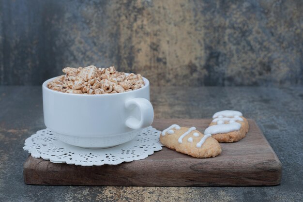 Taza blanca con galletas de Navidad sobre tabla de madera