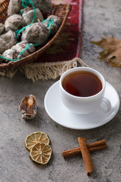 Una taza blanca de té caliente con frutos secos colocados sobre una mesa de piedra.