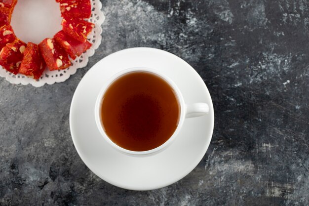 Una taza blanca de té caliente con postre en rodajas.