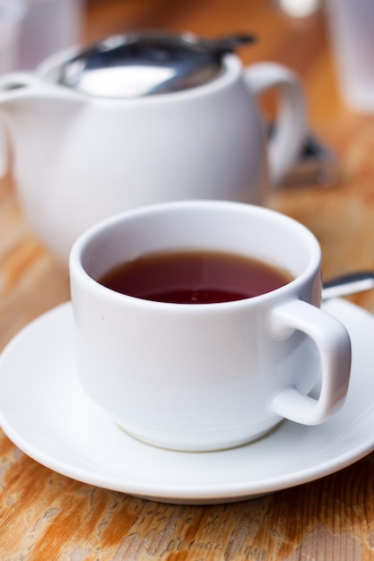 Taza blanca de té y una olla en la mesa de madera