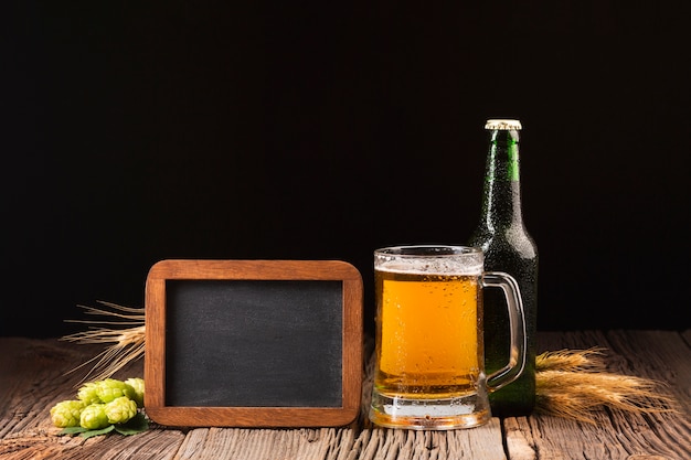 Foto gratuita taza y botella de cerveza sobre fondo de madera