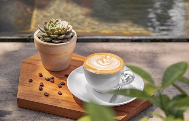 Taza de café con adornos y una planta sobre una superficie de madera.