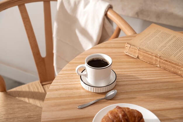Taza de café de alto ángulo y libro sobre la mesa