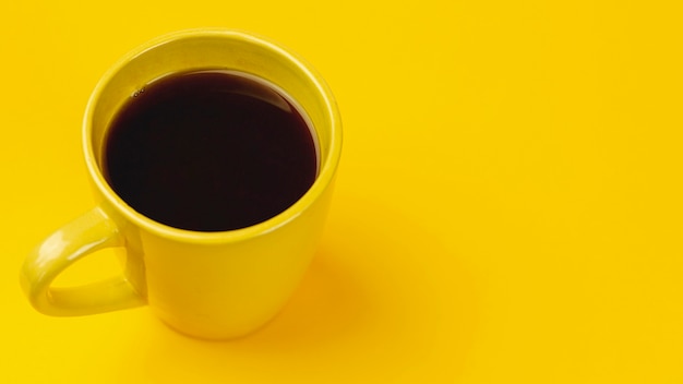Taza de café amarilla sobre un fondo amarillo