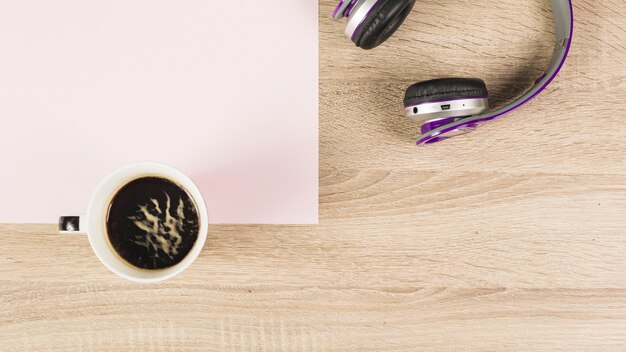 Taza de café; Auriculares y papel en blanco sobre fondo de madera