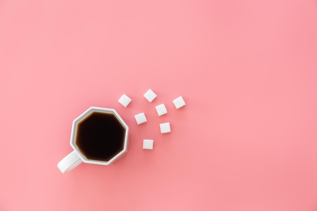 Foto gratuita taza de café y azúcar en cubos sobre un fondo rosa plano