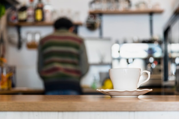 Taza de café blanco y platillo en el mostrador de café