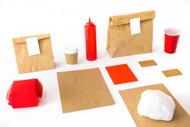Taza de café; botella de salsa; beber; hamburguesa y paquete sobre fondo blanco