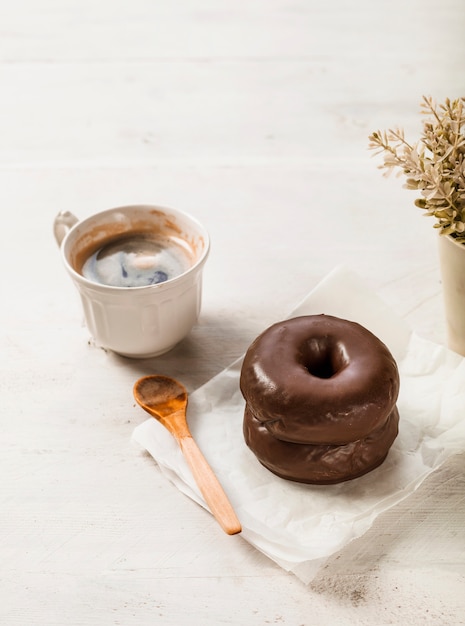 Foto gratuita taza de café; buñuelo de chocolate en la mesa de madera