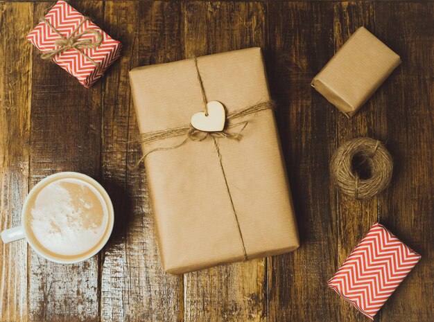 Taza de café y cajas de regalo artesanales con corazón rojo en una mesa de madera Vista superior