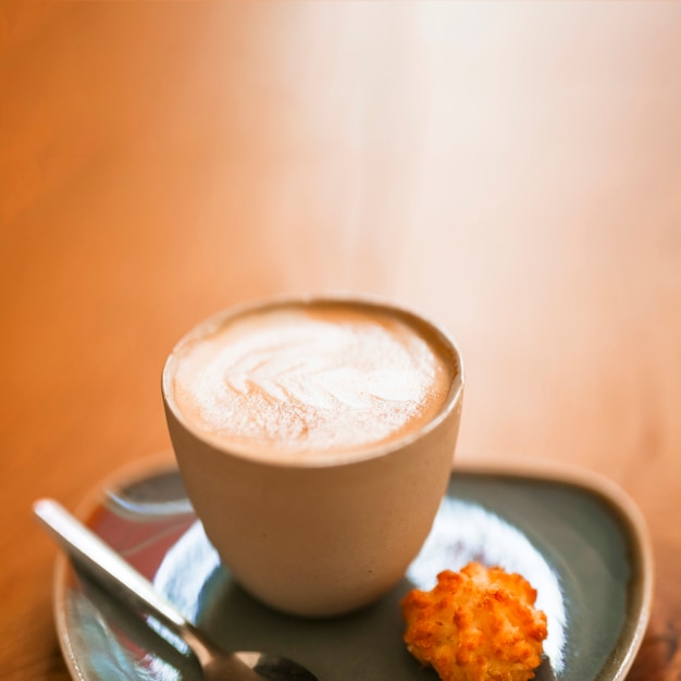 Una taza de café caliente del arte del latte en el contexto texturizado de madera