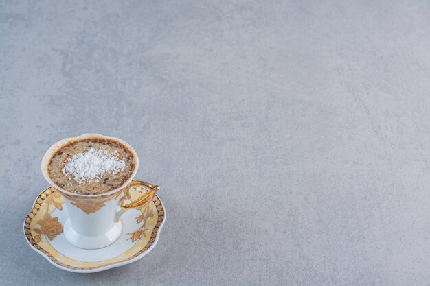 Taza de café caliente espumoso colocado sobre fondo de piedra.