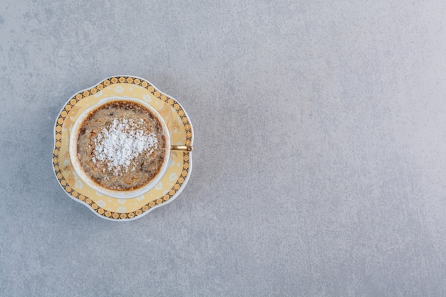 Taza de café caliente espumoso colocado sobre la mesa de piedra.