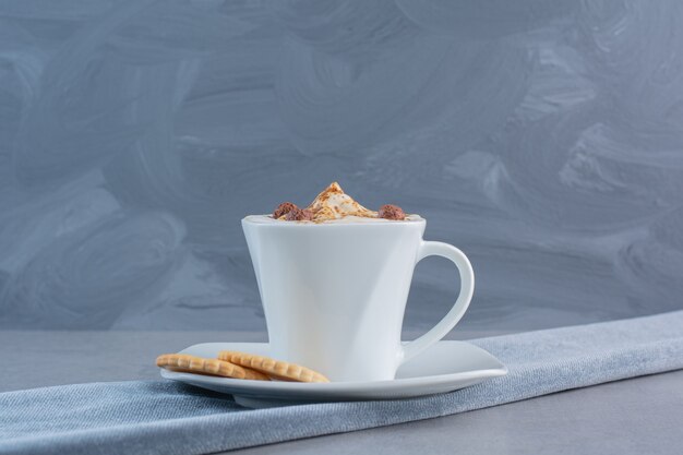 Taza de café caliente espumoso y galletas en la mesa de piedra.