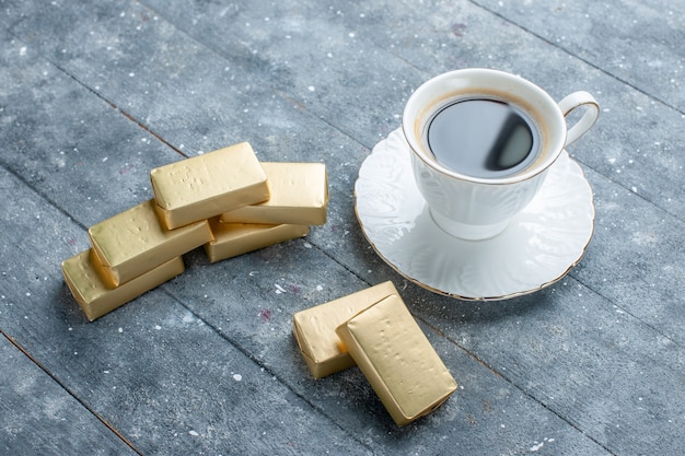 Taza de café caliente y fuerte con chocolate formado en oro sobre un escritorio azul, bebida de cacao de café caliente