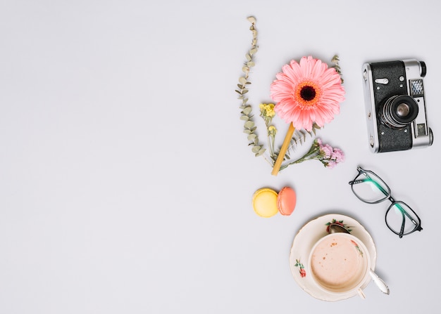 Foto gratuita taza de café con capullo de flor, cámara y gafas