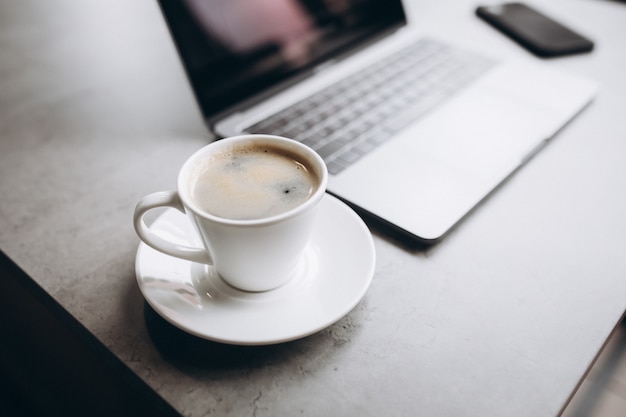 Taza de café y computadora en la mesa, vista superior