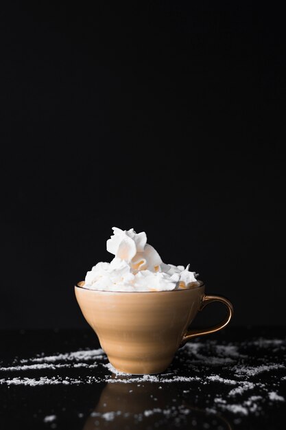 Taza de café con crema batida en la superficie negra