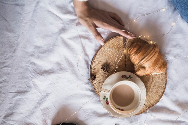 Taza de café y croissant en bandeja de madera