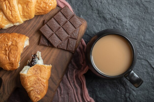 Una taza de café con croissants y barras de chocolate.