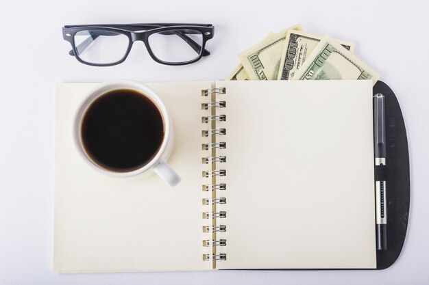 Taza de café en el cuaderno con gafas en el escritorio