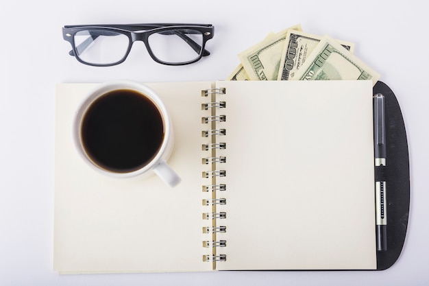 Taza de café en el cuaderno con gafas en el escritorio