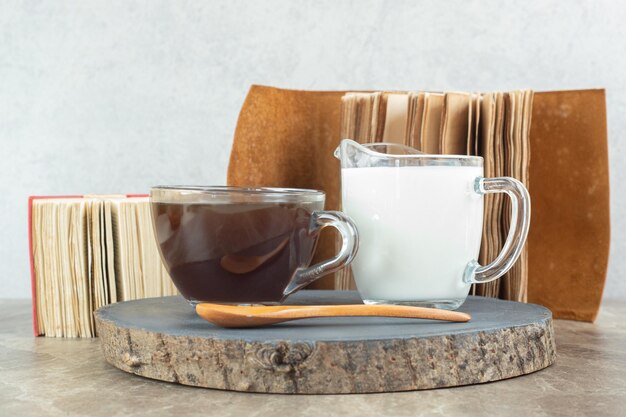 Taza de café, cuchara y leche en pieza de madera.