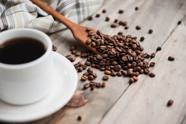 Foto gratuita taza de café con cuchara llena de granos