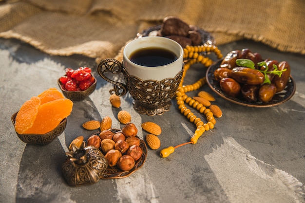 Taza de café con dátiles frutales y diferentes frutos secos.