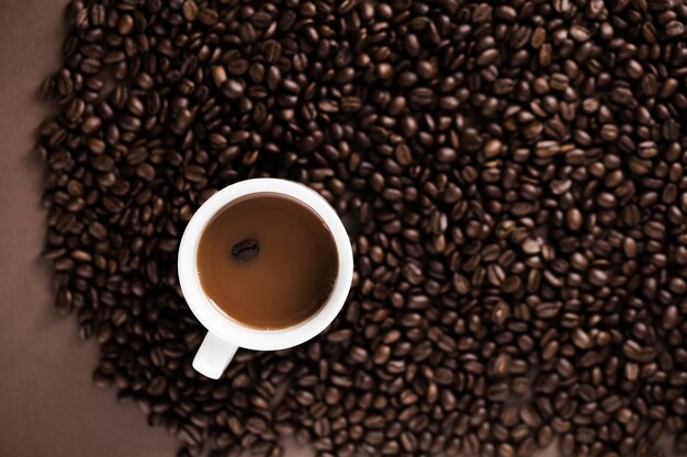 Taza de café deliciosa con el fondo de los granos de café