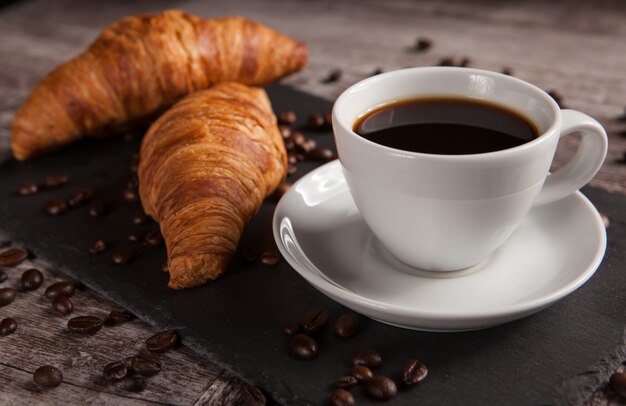 Taza de café con deliciosa pastelería y granos de café untados. Bocado matutino.