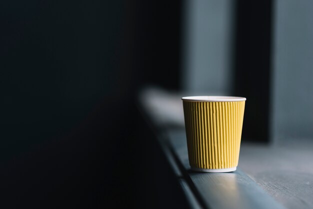 Taza de café desechable en el borde del alféizar de la ventana