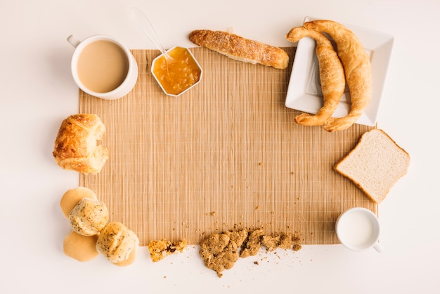 Taza de café con diferente panadería y mermelada en mesa