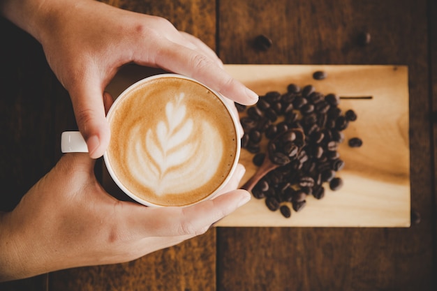 Una taza de café a disposición de mujeres en la textura de madera.