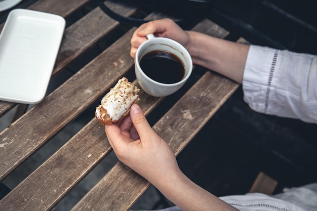 Taza de café y eclair en un primer plano de la mesa de madera