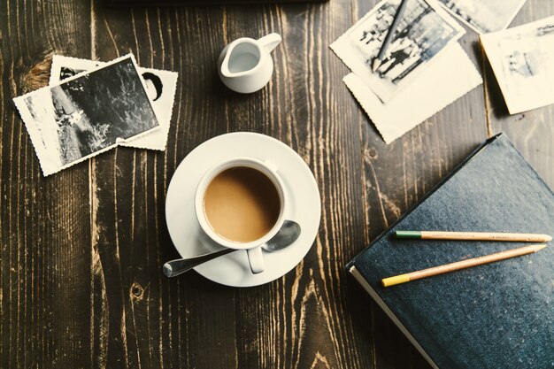 Taza de café se encuentra en la mesa de madera entre todas las fotos