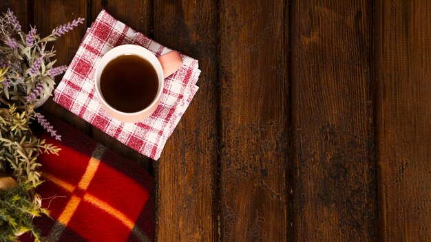 Taza de café, flores y manta de invierno en madera vieja