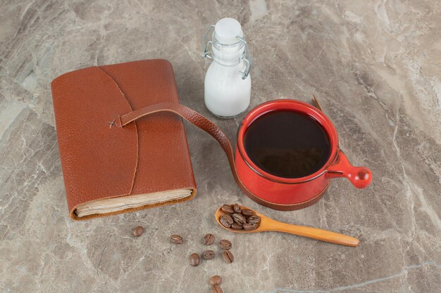 Taza de café, frijoles y cuaderno sobre superficie de mármol