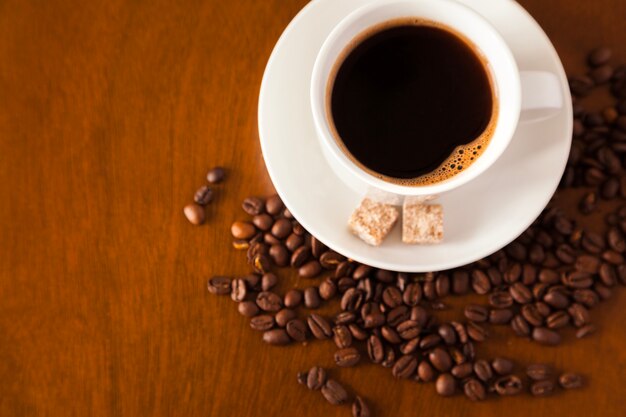 Taza de café y frijoles en la mesa de madera