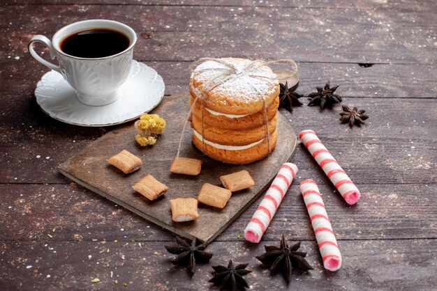 Taza de café fuerte y caliente junto con galletas y galletas sándwich en madera, pastel de frutas, galletas dulces