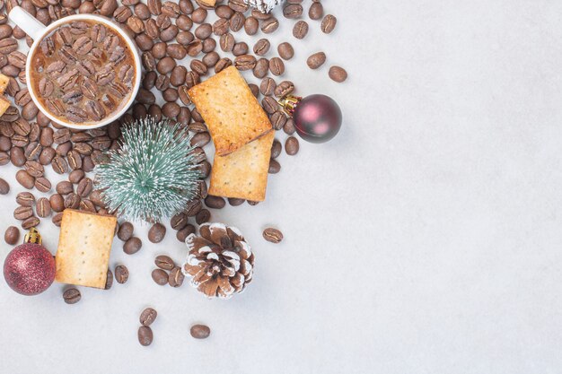 Taza de café, galletas y adornos navideños sobre la superficie de piedra.